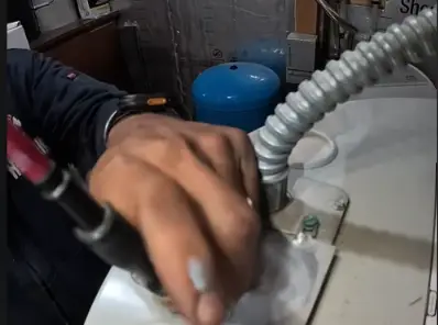Plumber installing an expansion tank near a water heater and flexible gas line