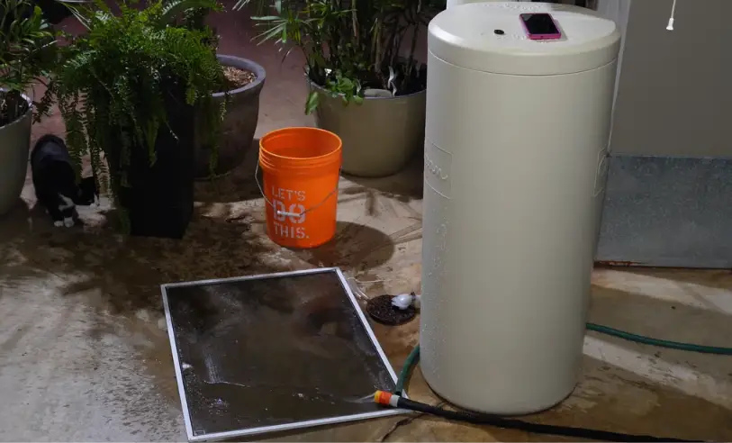 Water heater draining through a garden hose onto a mesh screen that catches sediment