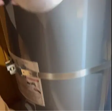 Metal seismic strap fastened around a water heater tank